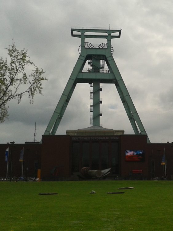 Futuristischer Förderturm mit grauem Himmel und grüner Struktur im Hintergrund. Bergbaumuseum Bochum, Stadtrundfahrt Bochum auf Ruhrdeutsch