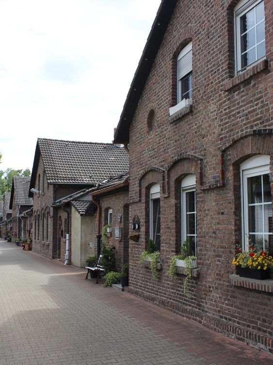 Engen Weg mit historischen Backsteinhäusern und Fensterkästen voller Blumen.
Klappheckenhof, Stadtrundfahrt Gelsenkirchen auf Ruhrdeutsch