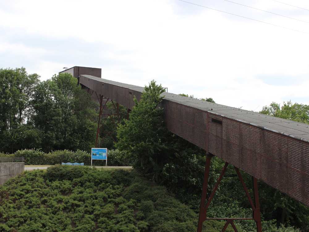 Bandbrücke Langgezogene Backsteinkonstruktion auf Stützen, umgeben von grüner Vegetation und einem Weg. Bandbrücke im Nordsternpark Gelsenkirchen