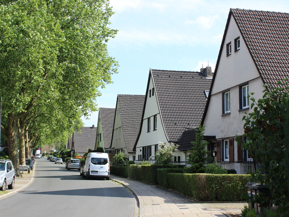Dahlhauser Heide Straße mit Wohnhäusern und Bäumen, ein Auto parkt am Straßenrand. Dahlhauser Heide Bochum