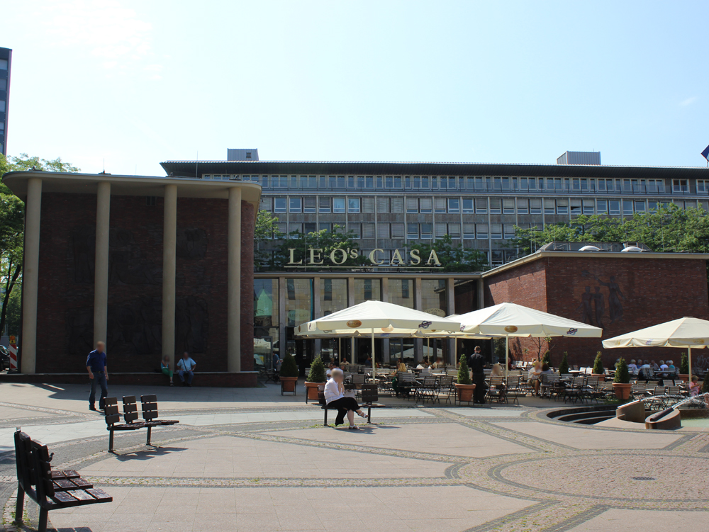 Europahaus Platz mit Café und Terrassen, umgeben von modernen Gebäuden und Bäumen. Europahaus Kennedyplatz, Essen