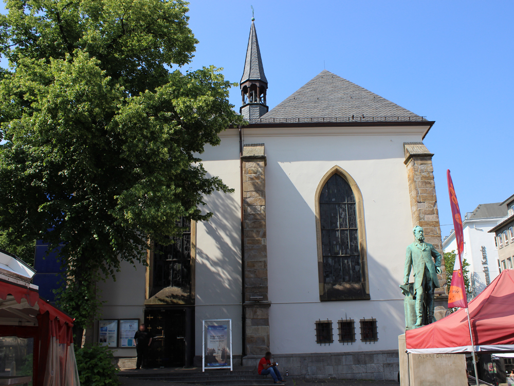 Marktkirche Kleine Kirche mit spitzem Turm und großen Fenstern, umgeben von Grünflächen und Statuen. Marktkirche, Essen