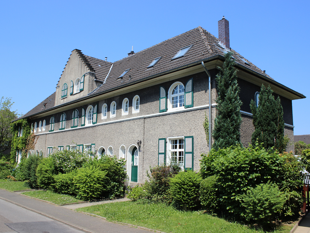 Haus in der Margarethenhöhe Zweistöckiges Gebäude mit grünem Fensterrahmen und umgebender Pflanzenlandschaft. Wohnhaus, Margarethenhöhe Essen.