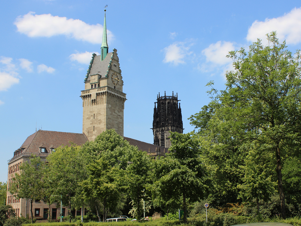 Rathaus Duisburg, Salvatorkirche Historisches Gebäude mit einem hohen Turm, umgeben von Bäumen und blauem Himmel. Rathaus Duisburg, Salvatorkirche