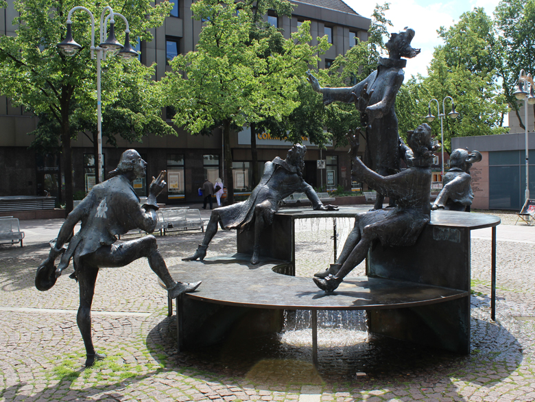 Kortum-Brunnen Bronzeskulpturen von im Kreis stehenden Figuren auf einem Platz in der Innenstadt, Kortum-Brunnen, Bochum