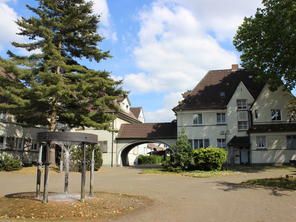 Beamtenplatz Ansicht eines ruhigen Innenhofs mit Bäumen und traditionellen Gebäuden. Beamtenplatz, Dahlhauser Heide Bochum