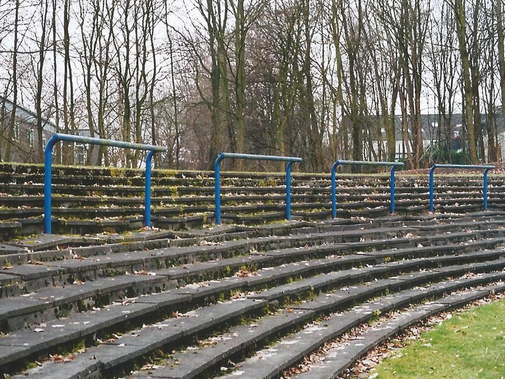 Südstadion Eintracht Gelsenkirchen Stufen einer Tribüne mit blauen Geländern, umgeben von Bäumen und Gras. Eintracht Gelsenkirchen, Südstadion, Fußballstadion,